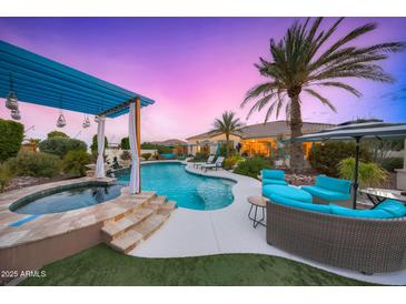 Stunning pool, spa, & outdoor seating area with pergola under a beautiful sunset at 10417 N 180Th Dr, Waddell, AZ 85355