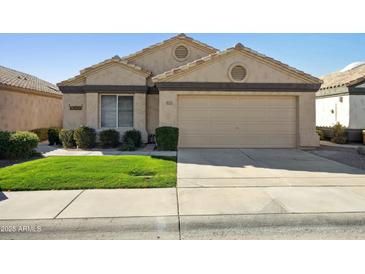 Tan house with a two-car garage and well-maintained lawn at 14535 W Zuni Trl, Surprise, AZ 85374