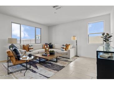 Bright living room features a large sectional sofa, modern decor, and plenty of natural light at 36378 W San Alvarez Ave, Maricopa, AZ 85138