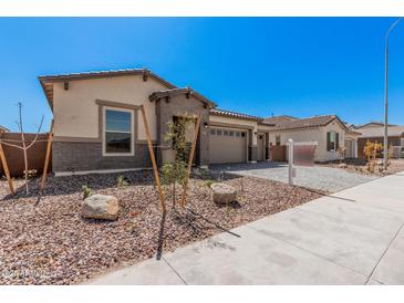 Charming single-story home featuring a neutral color scheme, manicured landscaping, and a welcoming two-car garage at 12007 W Parkway Ln, Avondale, AZ 85323