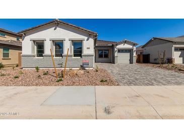 Charming single-Gathering home featuring a brick accent, landscaped front yard, and a paved driveway leading to the garage at 12012 W Parkway Ln, Avondale, AZ 85323