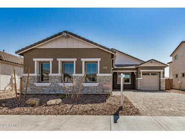 Charming single-story home featuring a stone facade, well-maintained landscaping, and a cozy, inviting entrance at 12015 W Parkway Ln, Avondale, AZ 85323