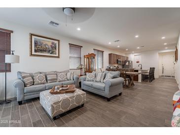 Bright living room features two comfy sofas, an ottoman, and wood-look floors at 21667 S 225Th Way, Queen Creek, AZ 85142