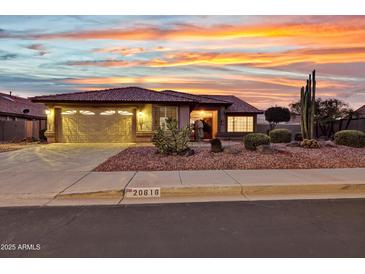 Charming single-story home featuring desert landscaping and a spacious two-car garage at sunset at 20616 N Ventana W Dr, Peoria, AZ 85373