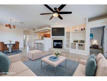 Bright living room featuring a fireplace, built-in shelves, ceiling fan, and open layout leading to the dining and kitchen areas at 11500 E Cochise Dr # 2090, Scottsdale, AZ 85259