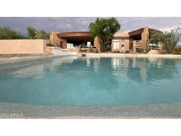 Inviting pool with cool, refreshing water and views of the stone-accented exterior of this desert home at 9853 E Sundance Trl, Scottsdale, AZ 85262