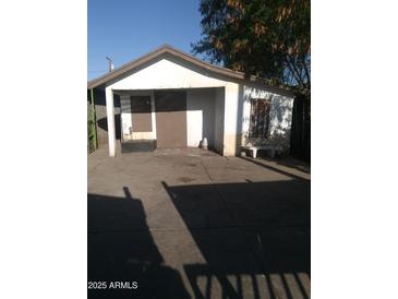 A garage sits on a concrete slab with doors covered with boards and a barred window with a bench at 1006 S 3Rd Ave, Phoenix, AZ 85003