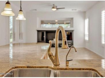 Bright kitchen featuring a stainless steel sink, gold faucet, and stone countertops at 13055 W Eagle Talon Trl, Peoria, AZ 85383