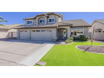 Charming two-story home featuring a three-car garage and manicured front lawn with lush green turf at 5249 E Hobart St, Mesa, AZ 85205