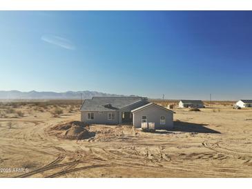 Newly constructed single-story home featuring modern architecture and neutral stucco, set against a desert backdrop at 25721 W Running Deer Trl, Wittmann, AZ 85361