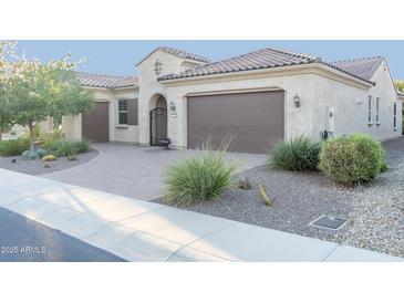 Tan house with brown garage door, landscaping, and a paved driveway at 27002 W Oraibi Dr, Buckeye, AZ 85396