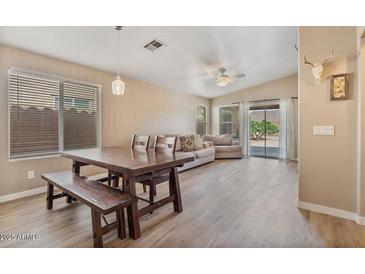 Open living room featuring wood floors, large windows, modern furniture, and sliding doors to the backyard at 1448 E Poncho Ln, San Tan Valley, AZ 85143