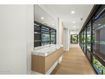 Bright hallway featuring hardwood floors, large windows, and a stylish marble topped console with a mirror at 7141 E Rancho Vista Dr # 2011, Scottsdale, AZ 85251