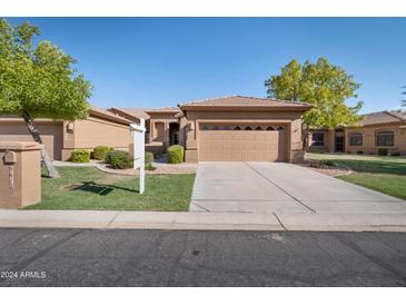 Single-story home with a two-car garage and well-manicured landscaping at 9612 E Champagne Dr, Sun Lakes, AZ 85248