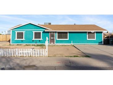 Charming single-story home featuring a colorful exterior, brown roof, and simple landscaping at 323 N 69Th Ave, Phoenix, AZ 85043