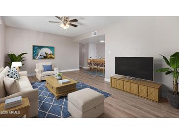 Bright living room features a ceiling fan, wood floors, an area rug, and a flatscreen TV atop a wooden credenza at 2633 W Ocotillo Rd # 3, Phoenix, AZ 85017