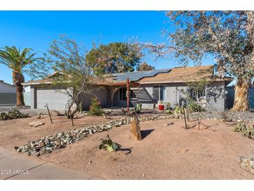 Ranch style home with a landscaped yard and solar panels at 1720 E Intrepid Ave, Mesa, AZ 85204