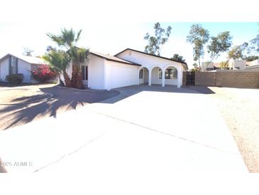 Single-story home boasting desert landscaping, arched porch, and a spacious driveway leading to an attached garage at 1446 S Revere --, Mesa, AZ 85210