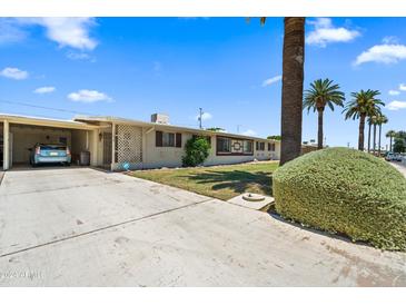 Charming single-story home features a covered carport, landscaped front yard, and mature palm trees at 11038 W Windsor Dr, Sun City, AZ 85351