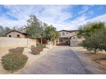 Stone house with gated entry and paved driveway at 8000 E Mariposa Grande Dr, Scottsdale, AZ 85255