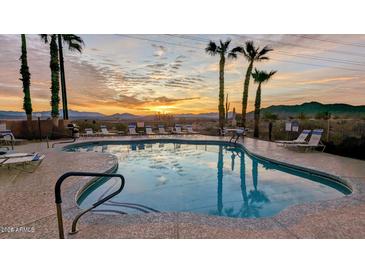 Community pool featuring a sunset view, palm trees, lounge chairs, and serene desert mountain views at 10401 N Saguaro Blvd # 224, Fountain Hills, AZ 85268