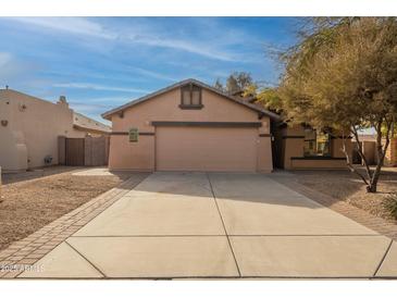 Tan house with a two-car garage and landscaped yard at 3011 E Colonial Pl, Chandler, AZ 85249