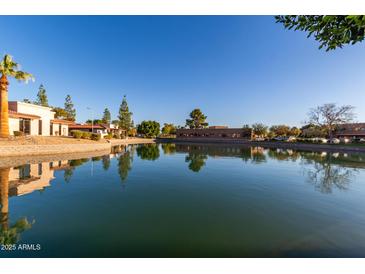 Scenic waterfront view of the community featuring lush landscaping and building reflections on the calm lake at 2107 S Paseo Loma --, Mesa, AZ 85202