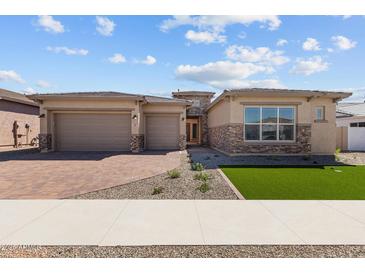 Charming single-story home featuring a brick driveway, three-car garage, and desert landscaping at 1021 W Ridge Rd, Apache Junction, AZ 85120