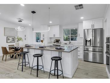 Bright, modern kitchen features stainless steel appliances, island with bar seating, and white cabinetry at 2233 E Behrend Dr # 132, Phoenix, AZ 85024