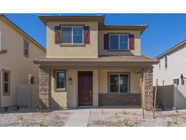 Inviting two-story home featuring a covered porch with stone accents and a well-maintained, low maintenance front yard at 15595 S 181St Dr, Goodyear, AZ 85338