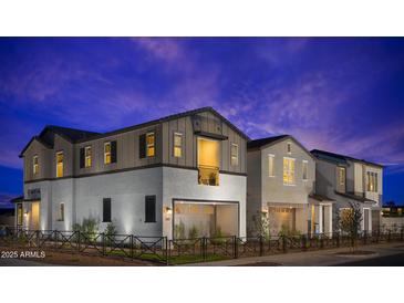 Charming two-story home featuring a balcony, well-lit windows, and a neatly fenced front yard, all under a captivating twilight sky at 2451 W Rowel Rd, Phoenix, AZ 85085