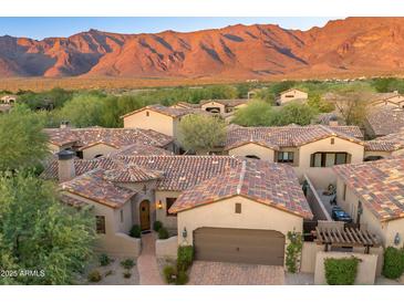 Stunning Tuscan-style home with colorful roof tiles and a lush, landscaped yard, set against a backdrop of majestic mountains at 3219 S Silverberry Ct, Gold Canyon, AZ 85118