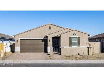 Tan house with brown garage door, black gate, and landscaping at 17738 W Coolidge St, Goodyear, AZ 85395