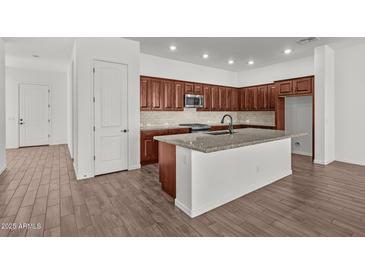 Modern kitchen features wood cabinets, granite counters, stainless appliances, and large center island at 12308 W Parkway Ln, Avondale, AZ 85323