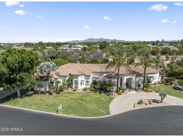 Stunning aerial view of a white home, circular driveway, lush landscaping, and mountain views in the distance at 2222 N Val Vista Dr # 3, Mesa, AZ 85213