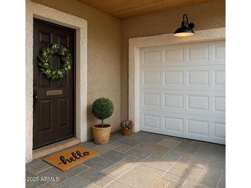 Inviting front entry with a dark door, wreath, charming hello doormat, and a white garage door at 1859 N Morris --, Mesa, AZ 85201