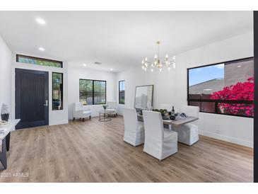Stylish living and dining area with bright natural light, wood floors, and elegant chandelier at 10646 E Butherus Dr, Scottsdale, AZ 85255
