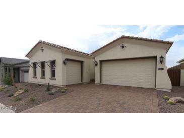 Charming single-story home featuring a three-car garage, desert landscaping, and a welcoming paver driveway at 21553 W Pierson St, Buckeye, AZ 85396