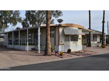 Charming mobile home with a covered porch and desert landscaping featuring cactus and decorative rocks at 9333 E University Dr # 89, Mesa, AZ 85207