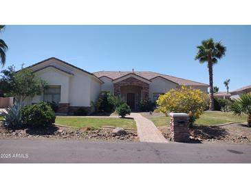 Charming single-story home featuring a manicured lawn, mature trees, and a stone-accented facade at 18029 W San Miguel Ave, Litchfield Park, AZ 85340