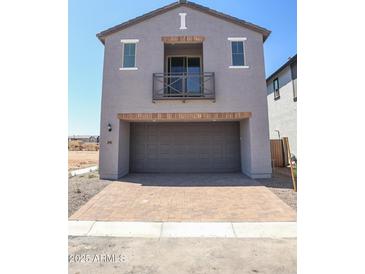 Modern home showcasing a gray exterior, balcony, brick-lined garage, and brick-paved driveway on a sunny day at 2445 W Rowel Rd, Phoenix, AZ 85085