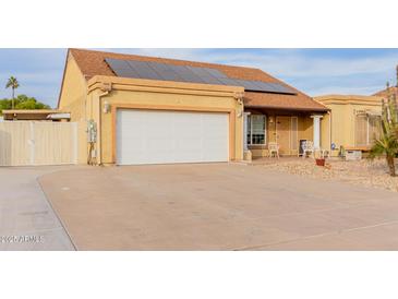 Charming single-story home featuring a two-car garage, desert landscaping, and solar panels at 6908 W Sunnyside Dr, Peoria, AZ 85345