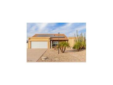 Desert landscape surrounds this single-story home with solar panels and a two-car garage at 6908 W Sunnyside Dr, Peoria, AZ 85345