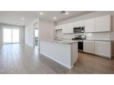 Modern kitchen with white cabinets, granite countertops, stainless steel appliances, and an island with a sink at 39980 W Bravo Dr, Maricopa, AZ 85138