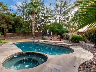 Inviting backyard pool and spa features a stone patio and lush landscaping, perfect for outdoor entertaining at 1201 E Le Marche Ave, Phoenix, AZ 85022