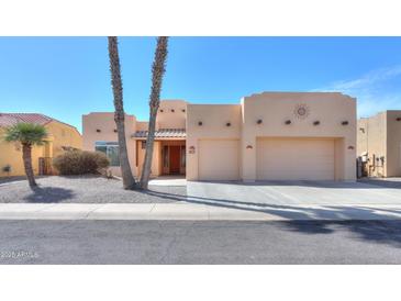 Beige stucco home with a two car garage, desert landscaping and palm trees at 923 W Crooked Stick Dr, Casa Grande, AZ 85122