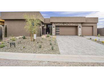 Stunning modern home with a desert landscape, stone accents, and a spacious driveway leading to a two-car garage at 37200 N Cave Creek Rd # 1023, Scottsdale, AZ 85262