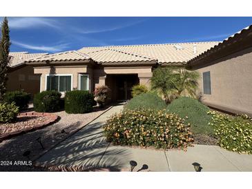 Tan house with tile roof, landscaped yard, and two-car garage at 13706 W Caballero Dr, Sun City West, AZ 85375