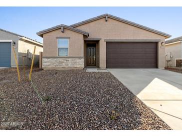 Tan house with brown garage door and stone accents at 9127 N 173Rd Ln, Waddell, AZ 85355