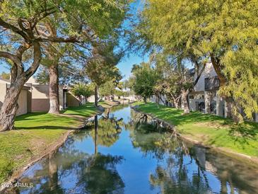 Tranquil canal-front view with lush landscaping and mature trees at 2232 W Lindner Ave # 44, Mesa, AZ 85202